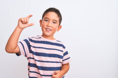 Güzel çocuk, izole edilmiş beyaz arka plan üzerinde sıradan çizgili tişört giyiyor gülümsüyor ve el hareketleriyle küçük boy işareti yapıyor ve kameraya bakıyor. Ölçü kavramı.