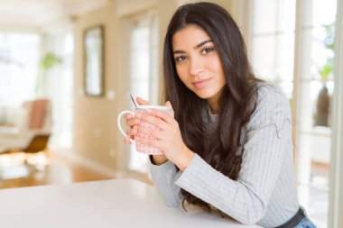 Güzel genç kız evde bir fincan kahve içme ve gülümseyen