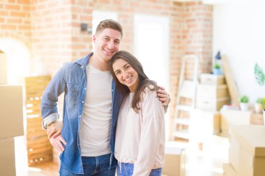Güzel genç çift yeni bir eve hareket, karton kutular etrafında yeni Aparment ayakta, mutlu ve sevgi gülümseyen sarılmak