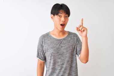 İzole edilmiş beyaz arka planda duran günlük tişört giyen genç Çinli adam başarılı bir fikir işaret ediyor. Heyecanlı ve mutlu. Bir numara..