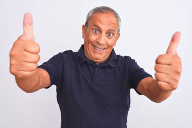 İzole edilmiş beyaz arka planda duran siyah polo giyen yaşlı gri saçlı adam elle olumlu jest yapıyor, gülümsüyor ve başarı için mutlu. Kazanan jest.