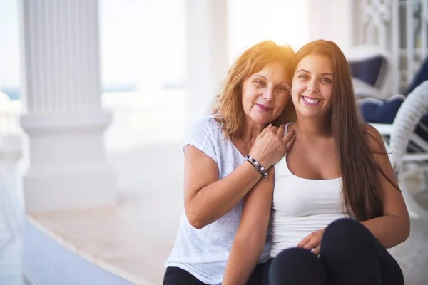 美しい母親と娘がテラスで抱き合って笑って座っている — ストック写真
