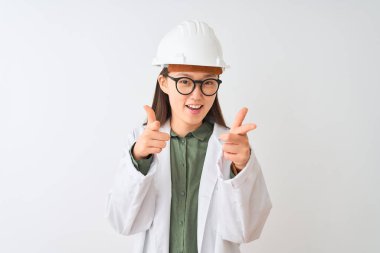 İzole edilmiş beyaz arka plan üzerinde ceket gözlüğü takan genç Çinli mühendis kadın mutlu ve komik yüzlü parmakları kameraya doğrultuyor. İyi enerji ve titreşimler.