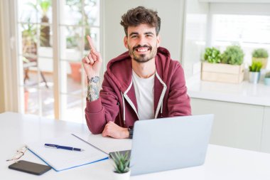 Bilgisayar laptop ve defter el ve parmak ile tarafına işaret çok mutlu kullanan genç öğrenci adam