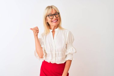 Orta yaşlı iş kadını gömlek ve gözlük takıyor. İzole edilmiş beyaz arka planda duruyor. Gülümsüyor, gülümsüyor..