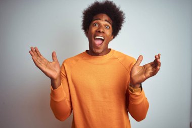 Siyah saçlı, turuncu kazak giyen genç bir Amerikalı çılgın ve başarısını kutluyor. Kolları havada ve gözleri açık, heyecanlı bir şekilde çığlık atıyor. Kazanan konsept