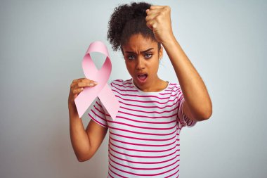 Kanser kurdelesi tutan genç Afro-Amerikalı bir kadın izole edilmiş beyaz arka planda kızgın ve sinirli bir şekilde bağırıyor, çıldırıyor ve el kaldırarak bağırıyor.