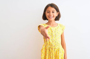 Sarı çiçekli elbise giyen güzel bir kız çocuğu izole edilmiş beyaz arka planda durup dostça gülümseyerek selamlama ve hoş geldin diyor. Başarılı bir iş..