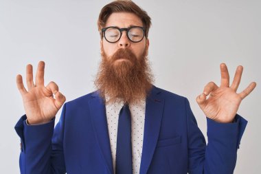 Genç kızıl İrlandalı işadamı takım elbise ve gözlük izole beyaz arka plan üzerinde dinlenmek ve gözleri parmakları ile meditasyon jest yapıyor kapalı gülümseyerek giyiyor. Yoga konsepti.