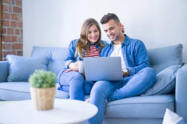 Genç çift bilgisayar laptop kullanarak kanepede oturan rahatlatıcı