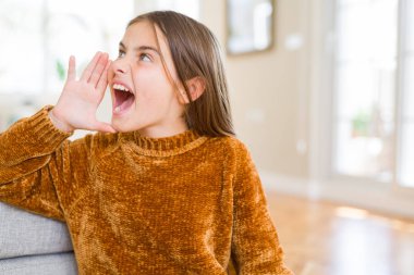 Güzel genç kız çocuk rahat kazak bağırıyor ve ağzını el ile yan yüksek sesle çığlık giyiyor. İletişim konsepti.