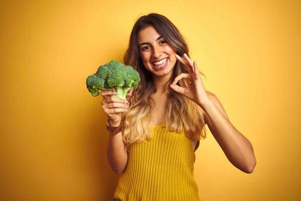 Sarı Izole Arka Planda Brokoli Yiyen Genç Güzel Bir Kadın — Stok fotoğraf