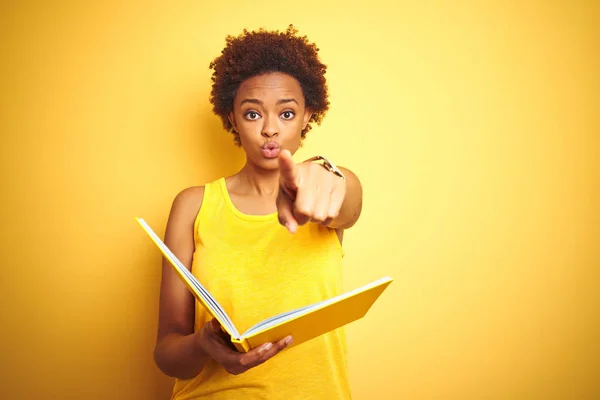 Afrikansk Amerikansk Kvinna Läser Bok Över Gul Isolerad Bakgrund Pekar — Stockfoto