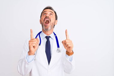 Orta yaşlı doktor ceketli ve steteskop takmış beyaz arka planda dikilen parmaklarıyla yukarı bakıyor ve kollarını kaldırıyordu..