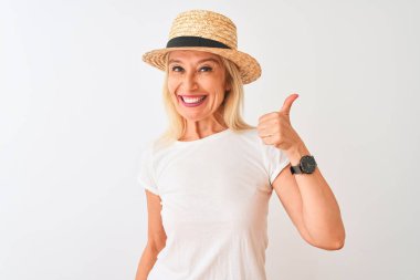 Sıradan tişört ve şapka giyen orta yaşlı bir kadın izole edilmiş beyaz arka planda durup mutlu bir el hareketi yapıyor. Kameraya bakıp başarıyı gösteren ifade onaylanıyor.