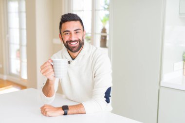 Yakışıklı adam gülümseyen bir fincan kahve içerken zevk 