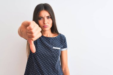 İzole edilmiş beyaz arka plan üzerinde duran mavi bir tişört giyen genç ve güzel bir kadın mutsuz ve kızgın görünüyor. Kötü ifade.