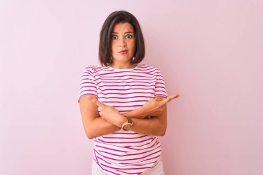 İzole edilmiş pembe arka plan üzerinde duran çizgili tişört giyen genç ve güzel bir kadın iki tarafı da işaret ediyor, farklı yönler farklı.
