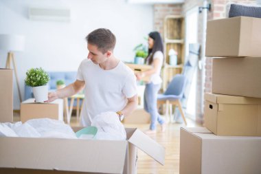 Karton kutuların etrafında duran genç ve güzel bir çift.