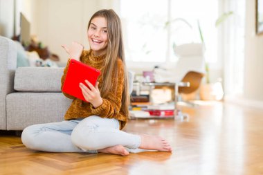 Güzel genç kız çocuk işaret ve başparmak kadar mutlu yüz gülümseyen tarafı ile gösterilen yerde oturan dijital dokunmatik tablet kullanma