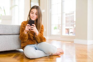 Güzel genç kız çocuk ciddi düşünme akıllı yüz üzerinde kendine güvenen bir ifade ile akıllı telefon kullanarak bir mesaj gönderme