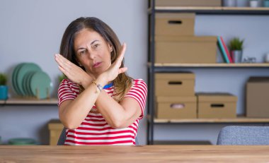 Orta yaş yaşlı kadın evde masada oturan Reddi ifade geçen silah olumsuz işaret yapıyor, kızgın yüz