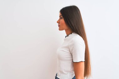 Yan bakarak izole beyaz arka plan üzerinde duran rahat t-shirt giyen genç güzel kadın, kendine güvenen gülümseme ile doğal yüz ile profil poz dinlenmek.