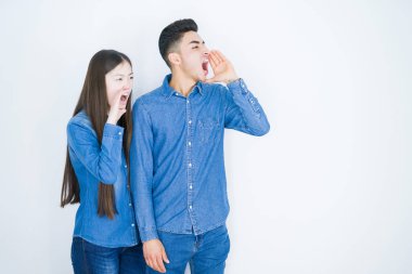 Güzel, genç Asyalı bir çift beyaz arka planda avazı çıktığı kadar bağırıp çığlık atıyorlar. İletişim konsepti.
