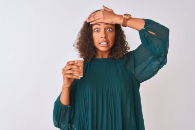 İzole edilmiş gri arka planda dikilen kahveyi içen genç Brezilyalı kadın, elleri başının üstünde, utanç ve şaşkınlık dolu, sinirli ve hayal kırıklığına uğramış bir halde. Hata için korku ve üzüntü.