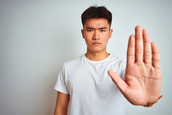 年轻的亚裔男子穿着T恤 站在孤立的白色背景上 手心停止歌唱 脸上带有消极而严肃的手势的警告表情 — 图库照片