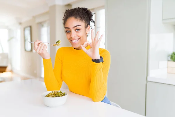 Young African American Woman Eating Healthy Green Vegatables Doing Sign — ストック写真