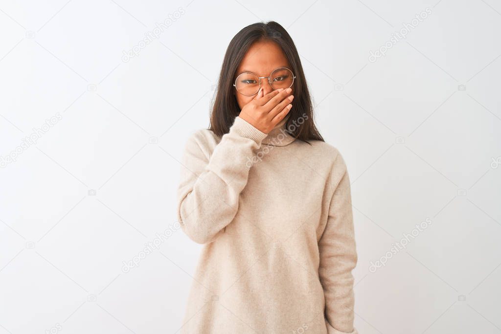 Young chinese woman wearing turtleneck sweater and glasses over isolated white background smelling something stinky and disgusting, intolerable smell, holding breath with fingers on nose. Bad smells concept.