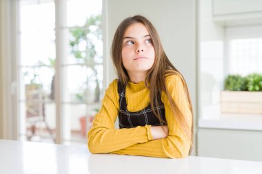 Sarışın, genç ve güzel bir kız. Evde sarı bir süveter giyiyor. Kollarını kavuşturmuş, ikna olmuş ve kendinden emin.