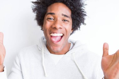 Beyaz arka planda afro saçı olan yakışıklı Afro-Amerikalı adam çılgın ve başarıyı kollarını kaldırıp heyecanla haykırarak kutluyor. Kazanan konsept