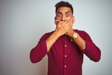 İzole edilmiş gri arka planda duran kırmızı şık gömlekli genç Hintli adam yanlışlıkla ağızlarını kapatarak şok geçirdi. Gizli konsept.