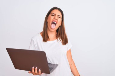 Güzel genç bir kadın beyaz arka plan üzerinde bilgisayar kullanarak çalışıyor. Komik bir ifadeyle dili dışarı çıkarıyor. Duygu kavramı.