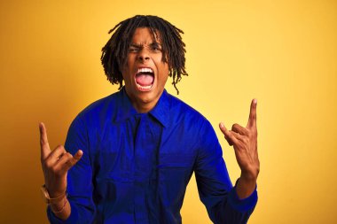 Sarı arka plan üzerinde mekanik üniforma giyen Afrikalı işçi elleri havada rock sembolü yaparken çılgınca bir ifadeyle bağırıyor. Müzik yıldızı. Ağır konsept.