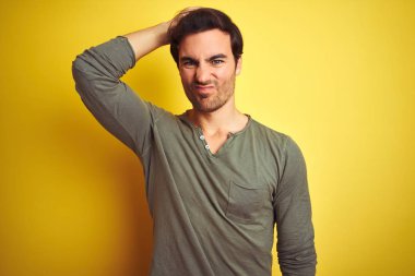 İzole edilmiş sarı arka planda duran sıradan tişörtler giyen genç yakışıklı adam soru sormayı merak ediyor. Şüpheyle kararsız, kafa kafaya düşünerek. Düşünceli kavram.