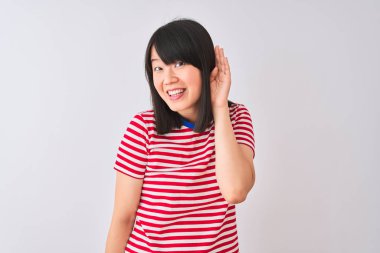 İzole edilmiş beyaz arka plan üzerinde kırmızı çizgili tişört giyen genç, güzel Çinli bir kadın kulağından girip kulağına gelen dedikoduları ya da dedikoduları dinliyor. Sağırlık kavramı.