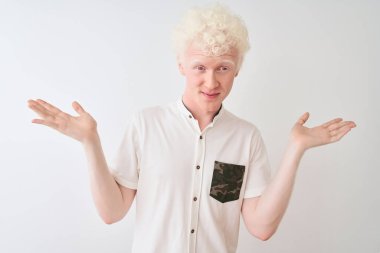 İzole edilmiş beyaz arka planda duran, kolları ve elleri havada, kafası karışmış genç, sarışın bir adam. Şüphe kavramı.