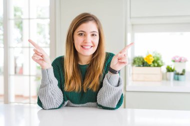 Güzel, iri yarı, sıradan çizgili süveter giyen, kendine güvenen, parmakları farklı yönleri gösteren genç bir kadın. Reklam için boşluk kopyala
