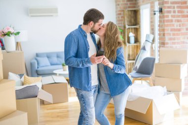 Genç çift karton kutular etrafında akıllı telefon kullanarak yeni bir eve hareket