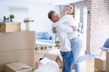 Karton kutular etrafında yeni evde sarılma köpek ile genç güzel çift