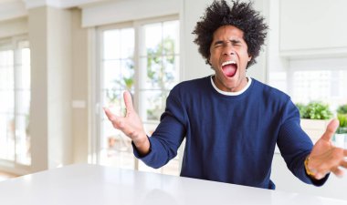 Genç afro-amerikan adam evde oturan rahat kazak giyen kızgın ve deli çığlık sinirli ve öfkeli, öfke ile bağırıyor. Öfke ve agresif kavram.