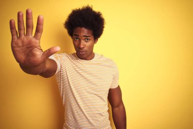 Afro saçlı, çizgili tişörtlü, izole edilmiş sarı arka planda duran Amerikalı adam avucunun içi gibi şarkı söylemeyi kesiyor. Yüzünde olumsuz ve ciddi bir jest olan uyarı ifadesi.