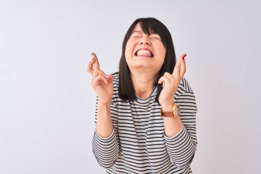 İzole edilmiş beyaz arka plan üzerinde siyah çizgili tişört giyen genç, güzel Çinli kadın umut ve gözler kapalı bir şekilde gülümseyerek işaret ediyor. Şans ve batıl inanç..