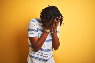 Sarı arka plan üzerinde çizgili gömlek giyen Afro-Amerikalı bir adam. Ağlarken suratını ellerle kapatan üzgün bir ifade. Depresyon kavramı.