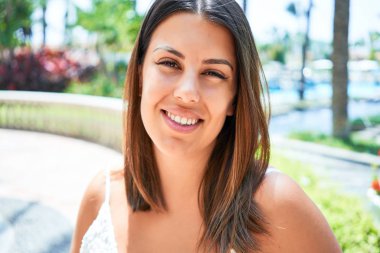 Genç, güzel bir kadın gülümsüyor. Mutlu, güneşli bir yaz gününün tadını çıkarıyor.