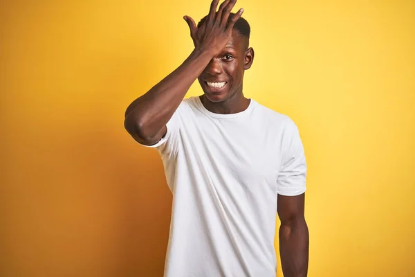 若いアフリカ系アメリカ人の男性が白いTシャツを着て 孤立した黄色の背景の上に立ってミスのために頭の上に手で驚いて エラーを覚えている 忘れられた悪い記憶の概念 — ストック写真