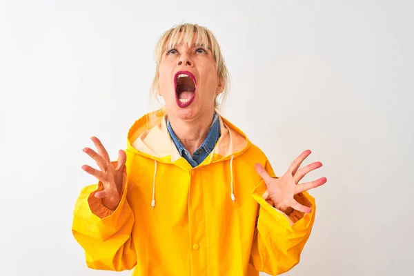 中年妇女穿着黄色雨衣 站在孤立的白色背景上疯狂地大叫着 带着咄咄逼人的表情和胳膊大喊大叫 沮丧的概念 — 图库照片